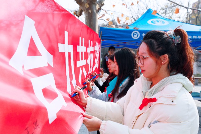 20231127中國(guó)石油大學(xué)（華東）青年學(xué)子在合力共抗艾滋的條幅上簽字，表達(dá)抗擊艾滋病的決心和信心  .jpg