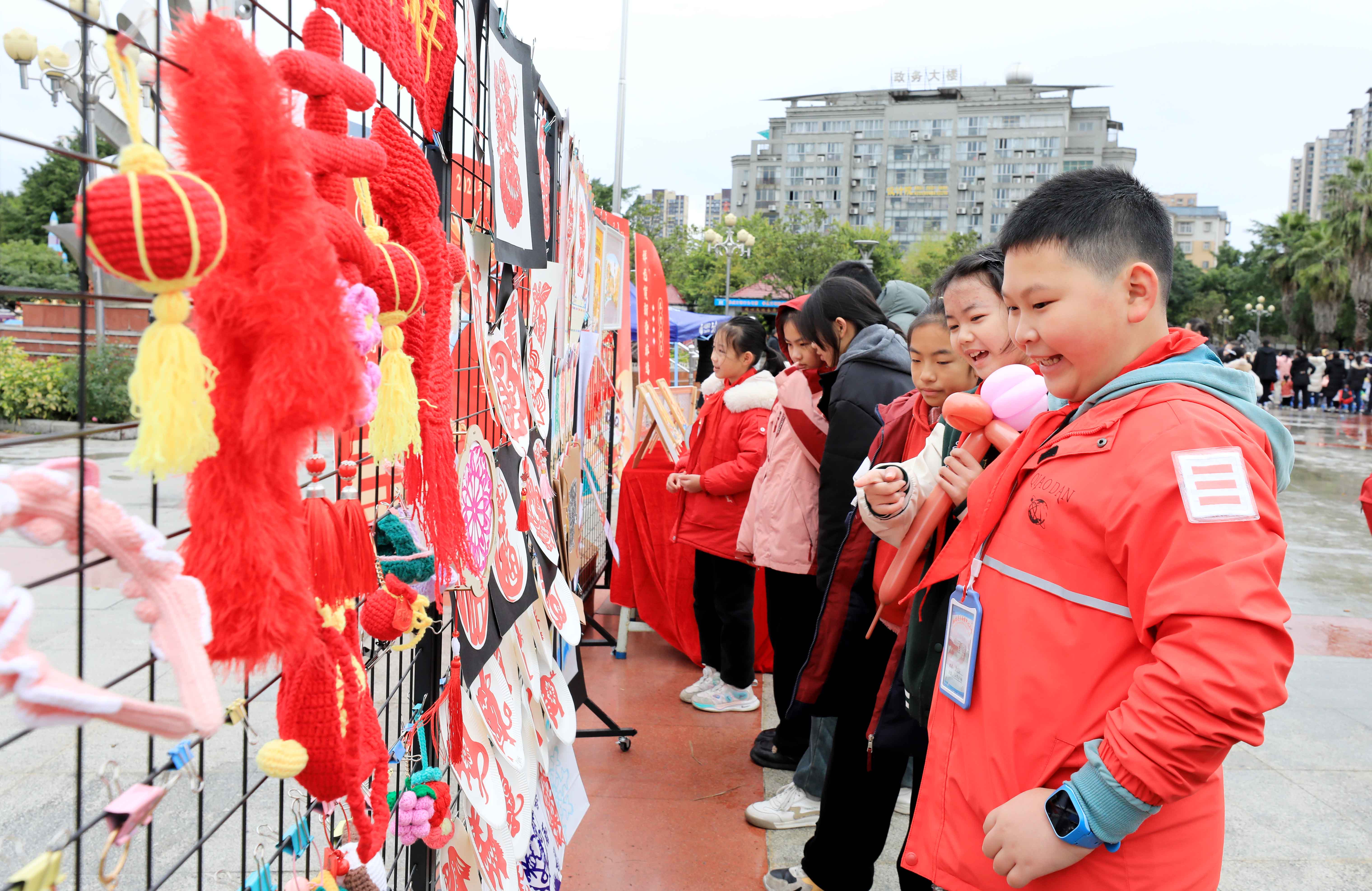 圖7：1月20日，在廣西柳州市融安縣長安廣場，學(xué)生在非遺集市上選購作品。（譚凱興 攝）.JPG