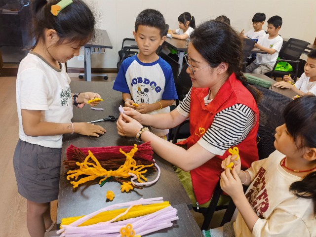 7月12日，在泰州市海陵區(qū)城東街道林湖社區(qū)，泰州市大浦小學(xué)“綠葉”暑期公益班的老師正在教孩子們一起做手工2（拍攝者：泰州市大浦中心小學(xué)  陳惠婷）.jpg